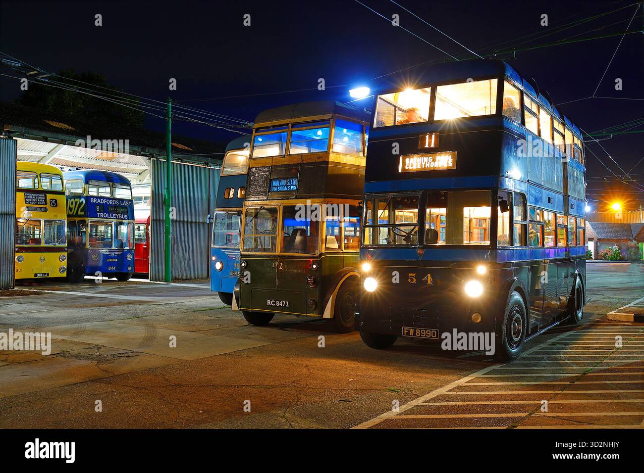 Una fila di filobus durante un evento al crepuscolo al Sandtoft Trolleybus Museum nel North Lincolnshire, Regno Unito Foto Stock