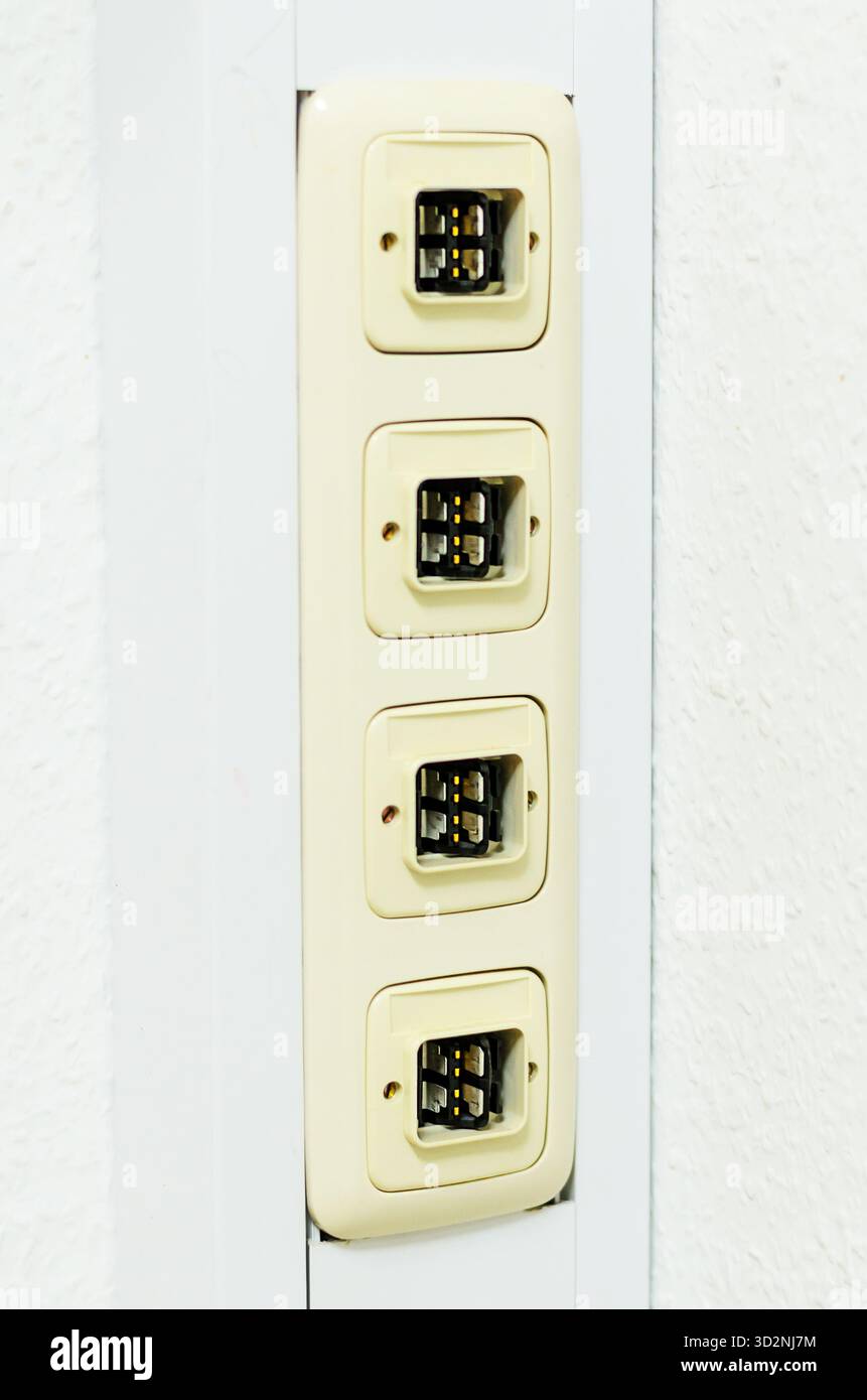 Questa immagine mostra un primo piano di un pannello delle prese telefoniche montato a parete con quattro porte, perfetto per le telecomunicazioni o i concetti di rete Foto Stock