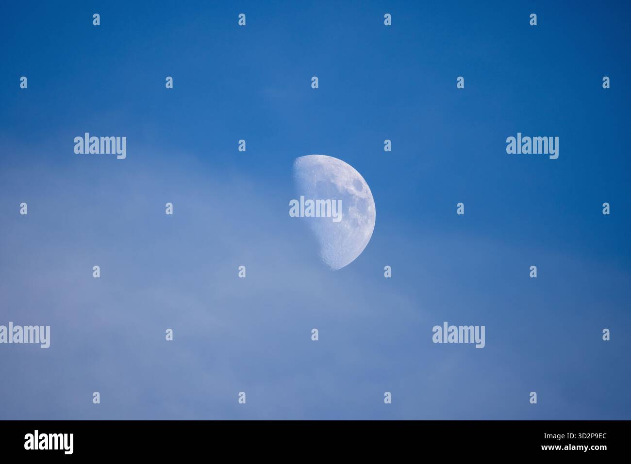 Primo piano della Luna alla luce del giorno contro un cielo blu che mostra crateri visibili e dettagli della superficie Foto Stock