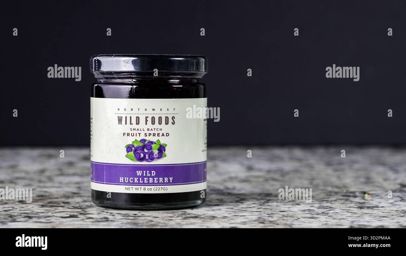 NORWALK, CT, USA - 30 OTTOBRE 2025: Un vaso di vetro riempito con frutta di mirtillo selvatico si trova su un ripiano in marmo. Lo sfondo scuro si evidenzia Foto Stock