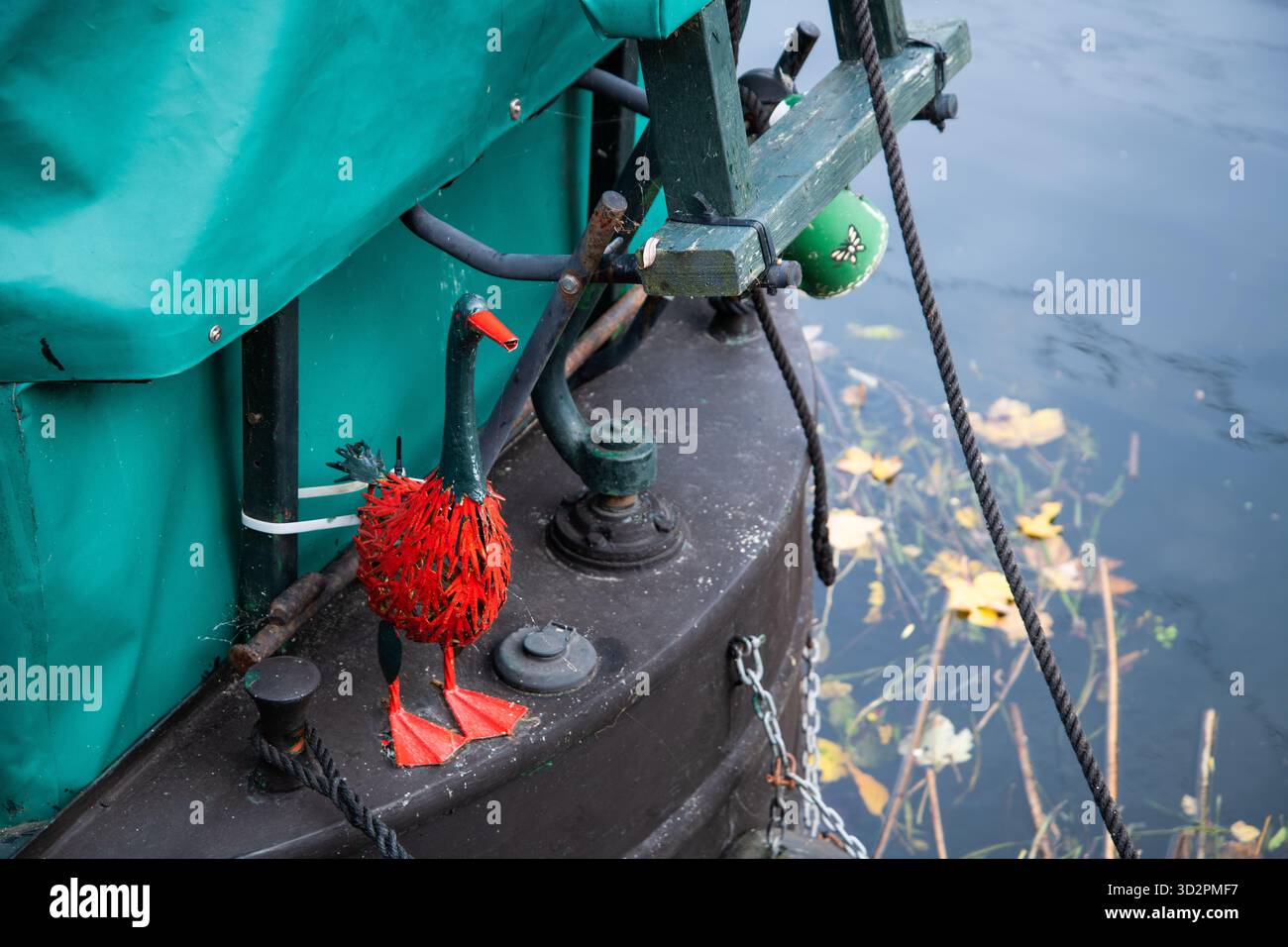 Sulla poppa di una barca sul canale si trova un'anatra decorativa in ferro dipinta di rosso e verde. Tradizionale ornamento in barca stretta su un canale del Regno Unito. Foto Stock
