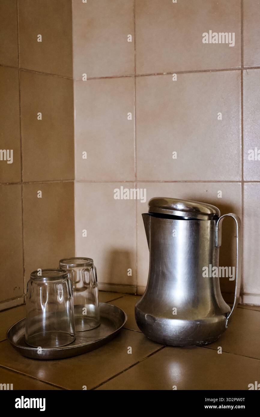 Brocca e bicchieri in metallo su un vassoio in una camera presso il Park Guest House, Sri Aurobindo Ashram, Puducherry, incarnando la tranquilla semplicità dell'Ashram. Foto Stock