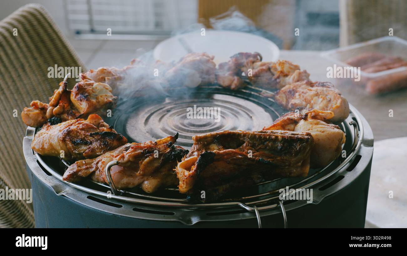 Barbecue di pollo grigliato affumicato all'aperto con pinze, carne arrosto succosa in cottura con affumicatura spessa durante il picnic estivo, preparazione barbecue sul cortile Foto Stock