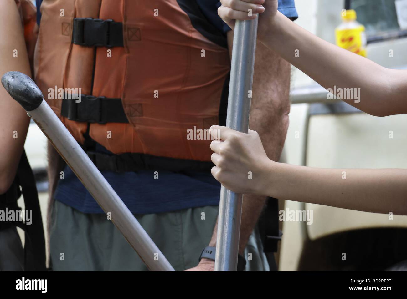 Mani umane che tengono saldamente la pagaia con la messa a fuoco, giubbotto salvagente visibile, simboleggiano le attività ricreative all'aperto e l'avventura. L'attrezzatura di sicurezza garantisce la sicurezza e la Foto Stock