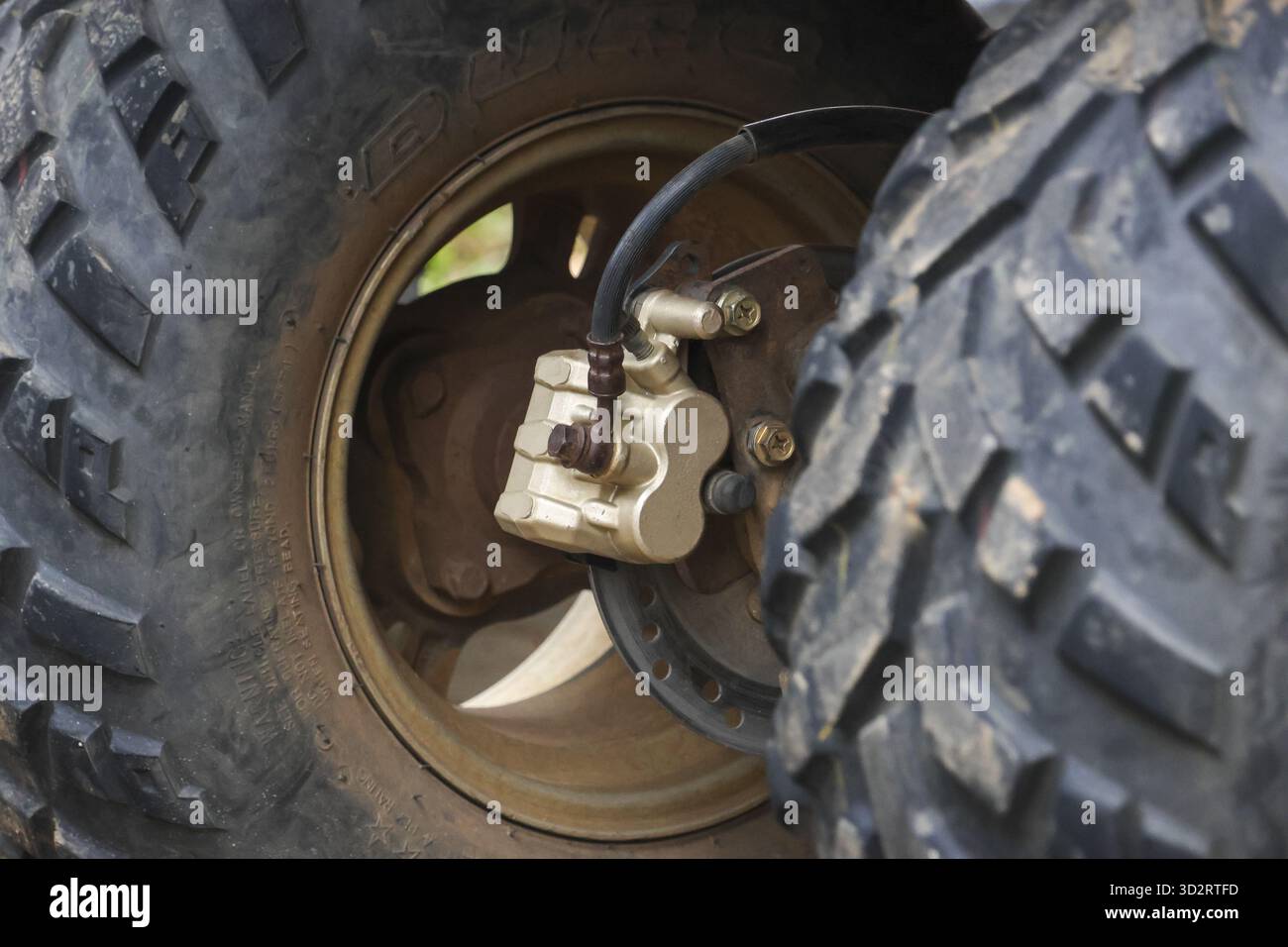 Il primo piano di uno pneumatico ATV e di una pinza dei freni di un veicolo All Terrain mostra una struttura robusta e dettagli meccanici, trasmettendo un senso di avventura e durata Foto Stock