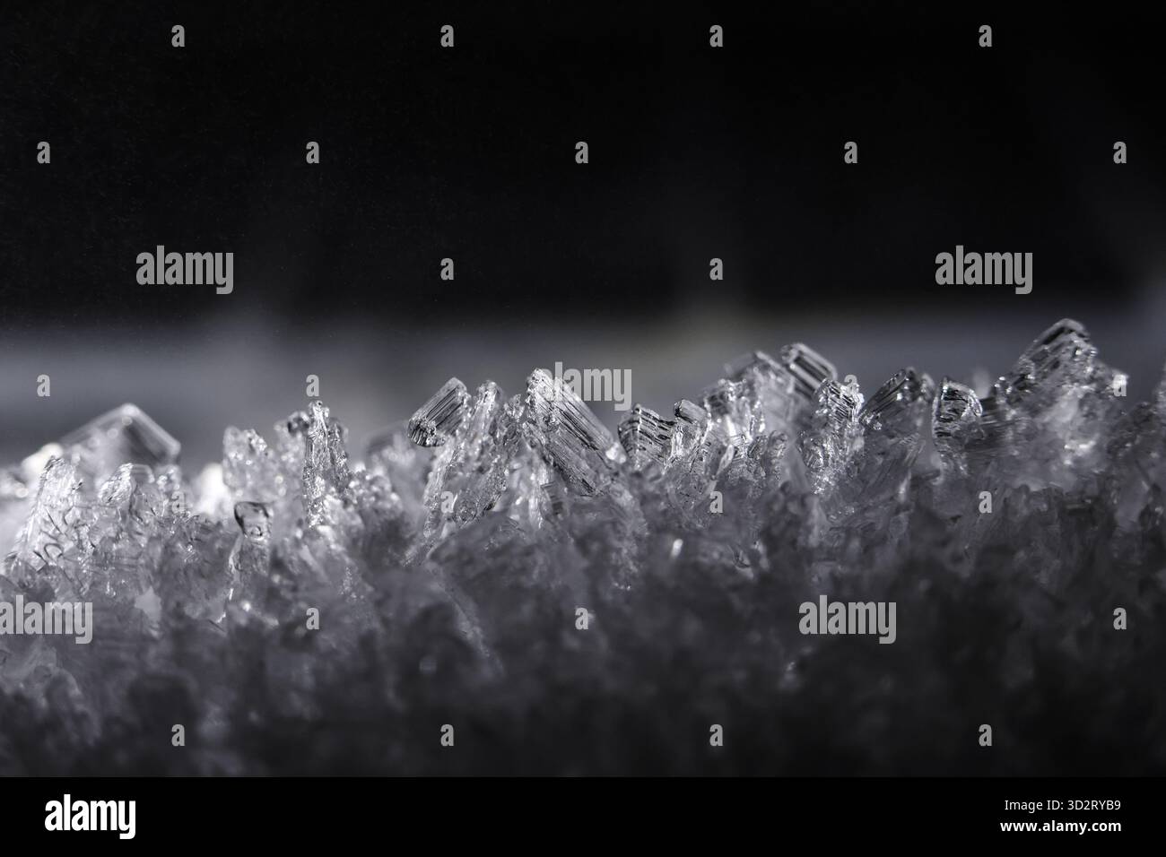 Misteriosa vista macro ravvicinata di cristalli di ghiaccio frastagliati e nitidi su sfondo scuro e freddo. Questa astratta scena invernale mostra un'intricata trama ghiacciata e pianto Foto Stock