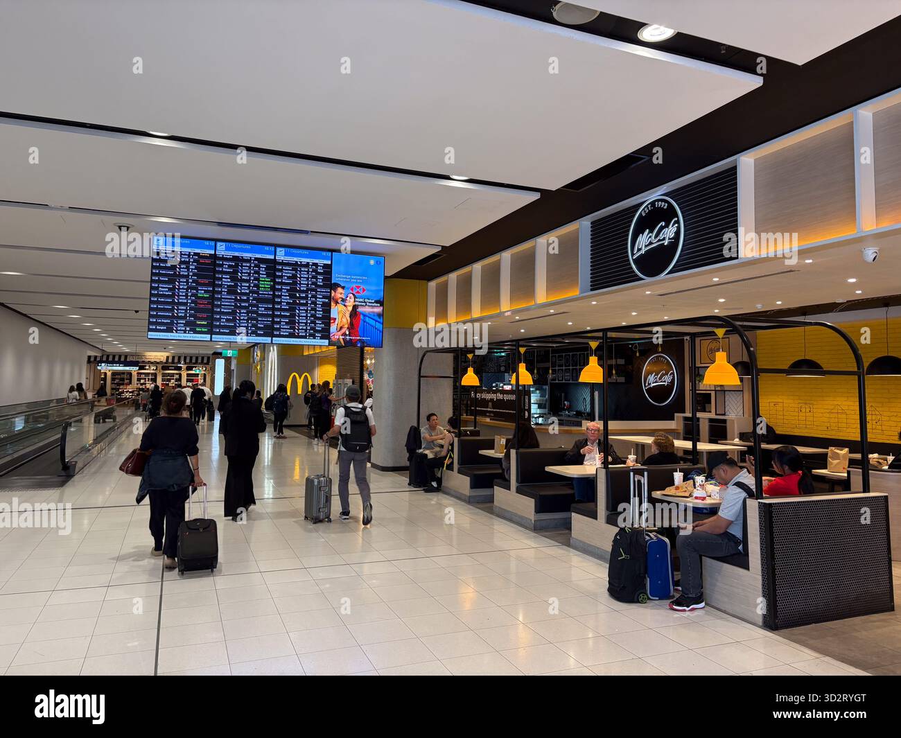 McDonald's McCafé, ristorante fast food all'interno del trafficato terminal dell'aeroporto di Sydney, Australia, con viaggiatori a piedi e altri ristoranti. Un grande fli Foto Stock