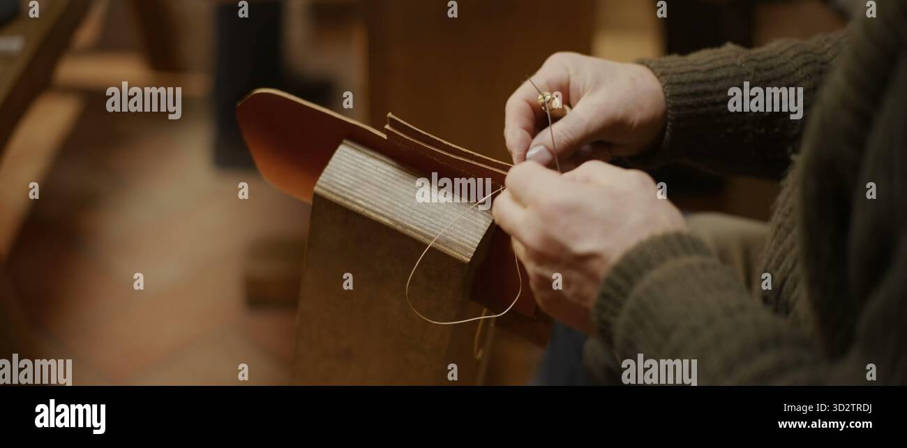 Cucitura mani in pelle marrone-rossastro con filo in un morsetto pony in legno Foto Stock