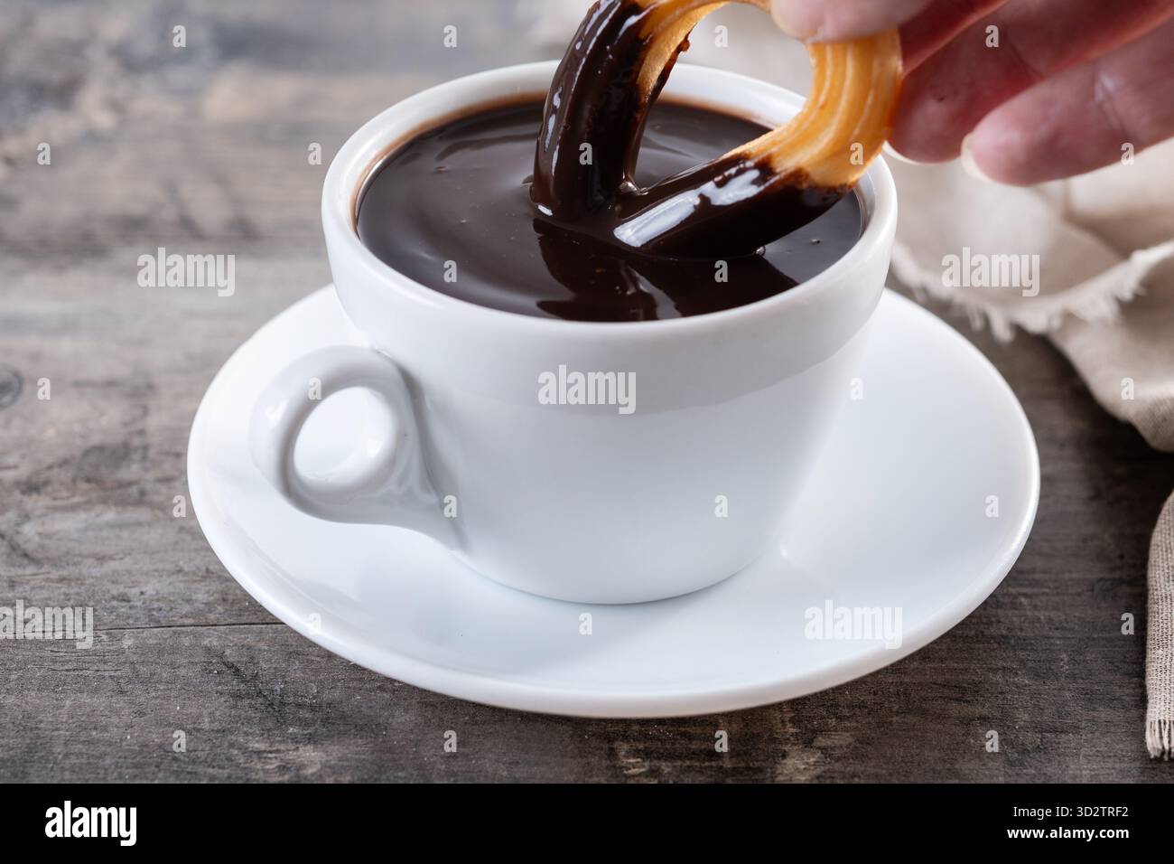 Cioccolata calda spessa in una tazza bianca con churros su un tavolo di legno Foto Stock
