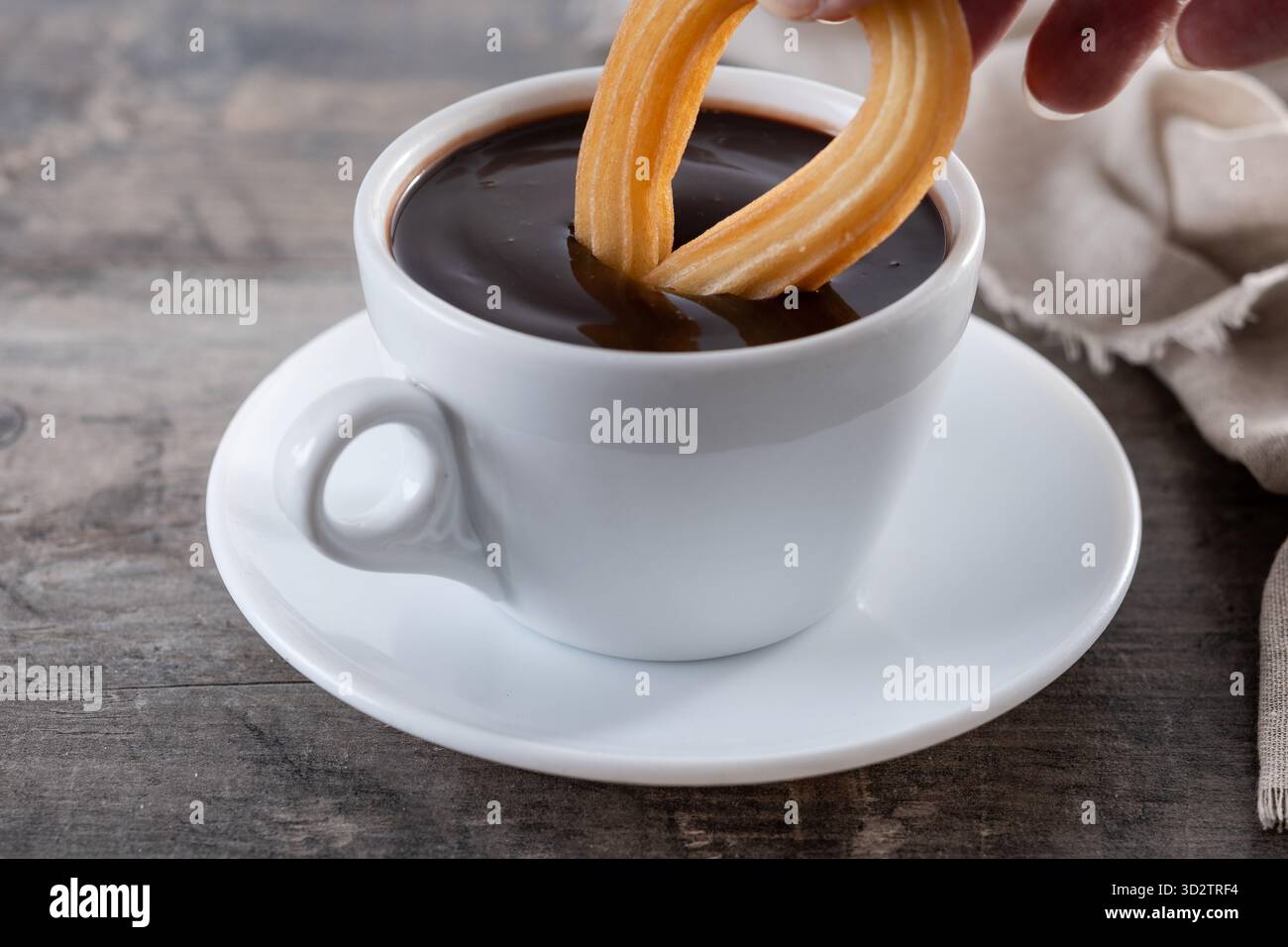 Cioccolata calda spessa in una tazza bianca con churros su un tavolo di legno Foto Stock