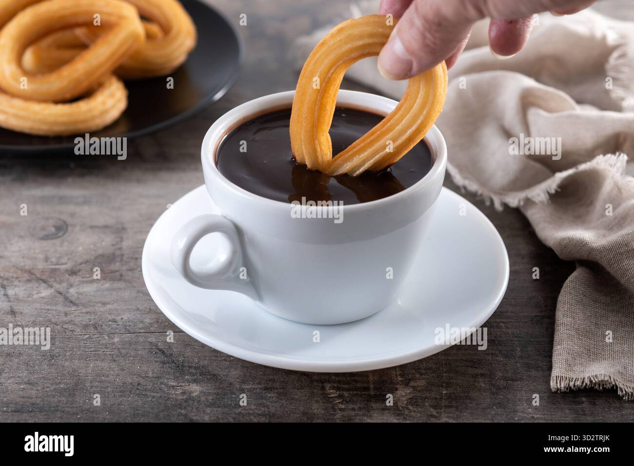 Cioccolata calda spessa in una tazza bianca con churros su un tavolo di legno Foto Stock