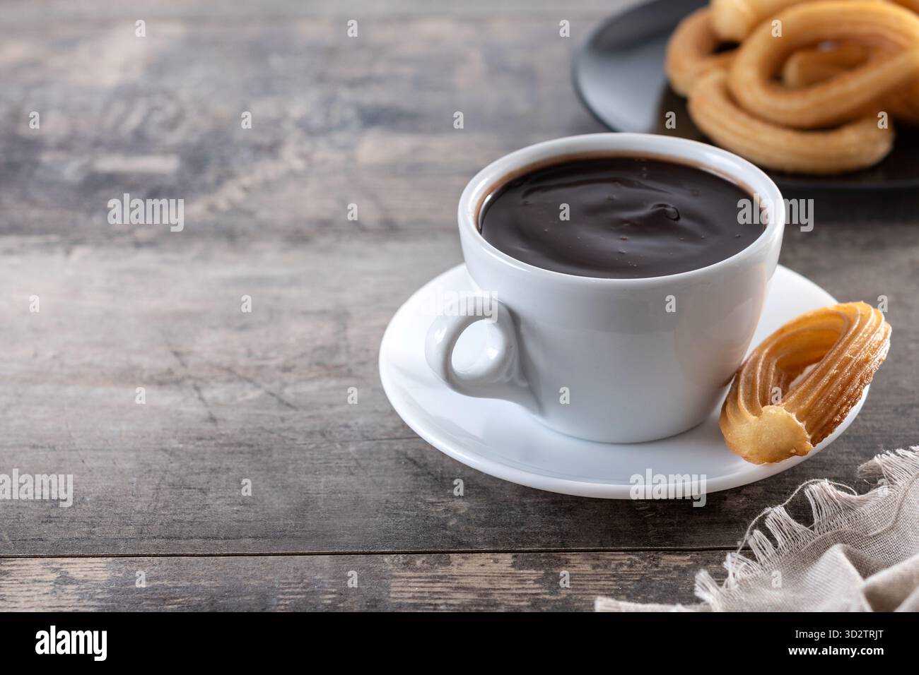 Cioccolata calda spessa in una tazza bianca con churros su un tavolo di legno Foto Stock