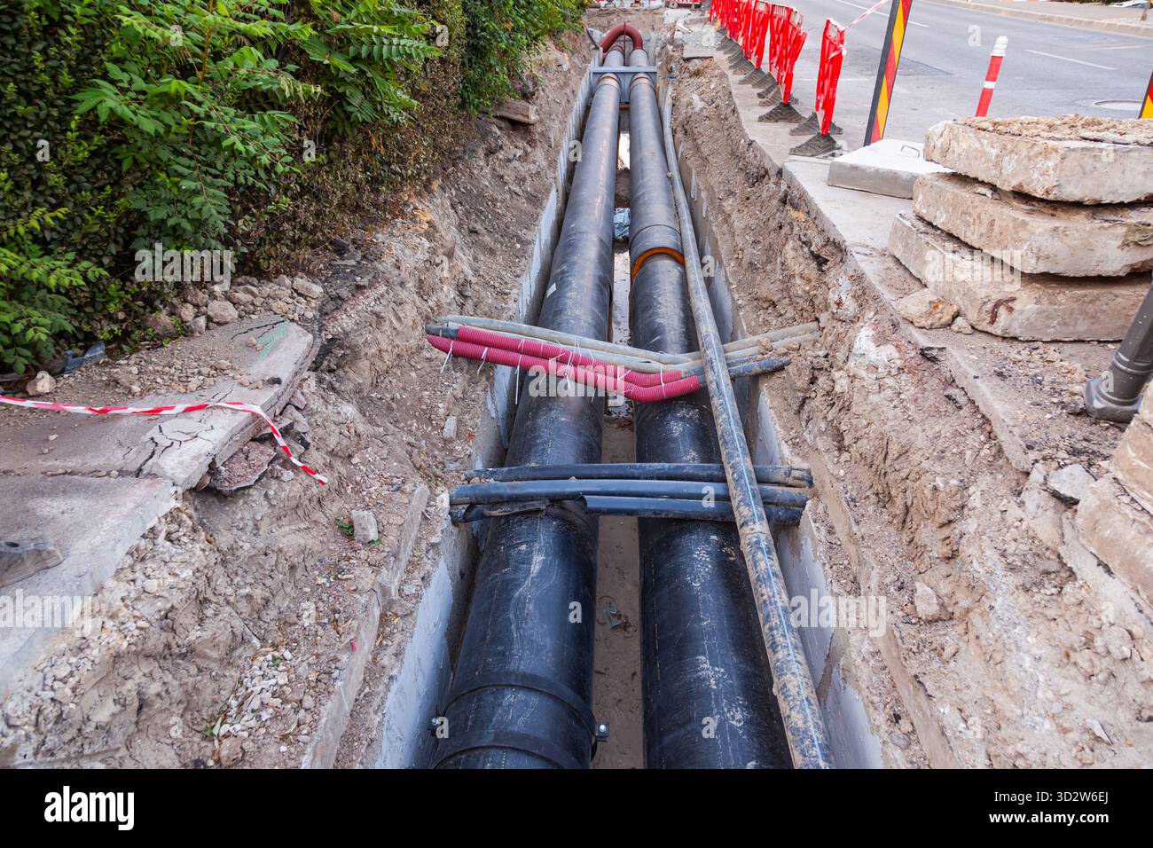 Posa di nuovi tubi dell'acqua di grande diametro nel terreno della città. Foto Stock