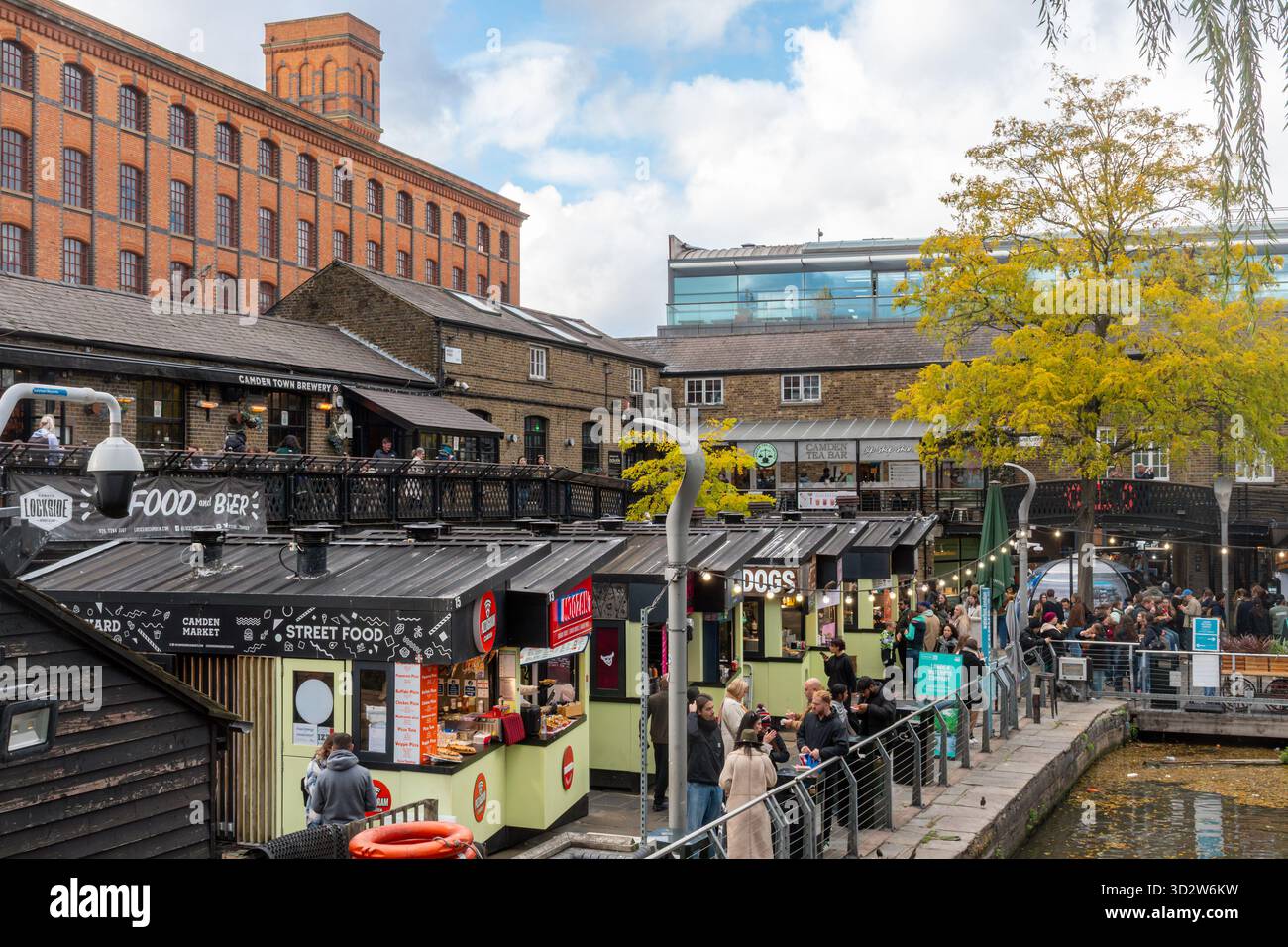 Persone ai chioschi di cibo di Camden Market, una popolare attrazione turistica di Camden Town, Londra, Inghilterra, Regno Unito, con l'Interchange Building Foto Stock