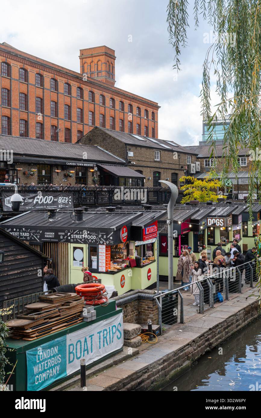 Persone ai chioschi di cibo di Camden Market, una popolare attrazione turistica di Camden Town, Londra, Inghilterra, Regno Unito, con l'Interchange Building Foto Stock