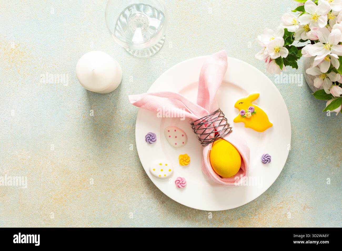 Un vivace tavolo pasquale è caratterizzato da un piatto ben organizzato con un uovo avvolto, biscotti decorati e fiori freschi, che creano un'atmos gioiosa Foto Stock