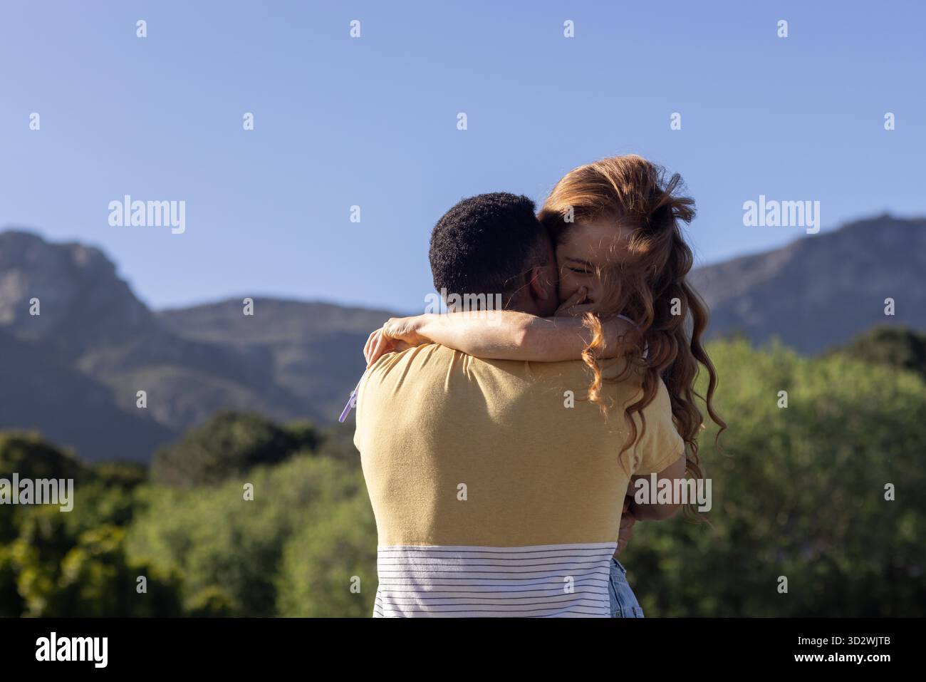 Giovane coppia che abbraccia l'aria aperta con montagne sullo sfondo, condividendo momenti di gioia. Amore, natura, felicità, romanticismo, avventura, Scenic || modello rilasciato Foto Stock