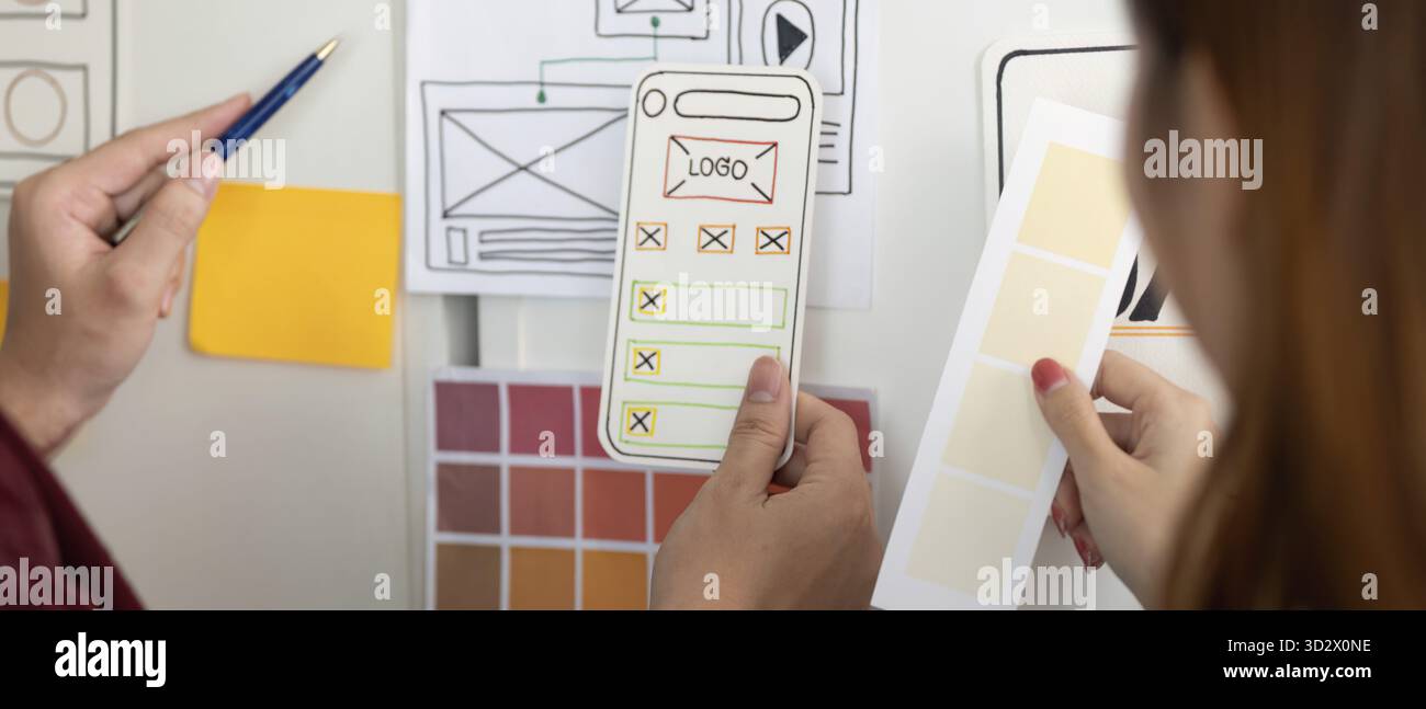 Mani che presentano modelli di design e tavolozze di colori per un'app mobile, evidenziando il processo di progettazione UX e UI Foto Stock
