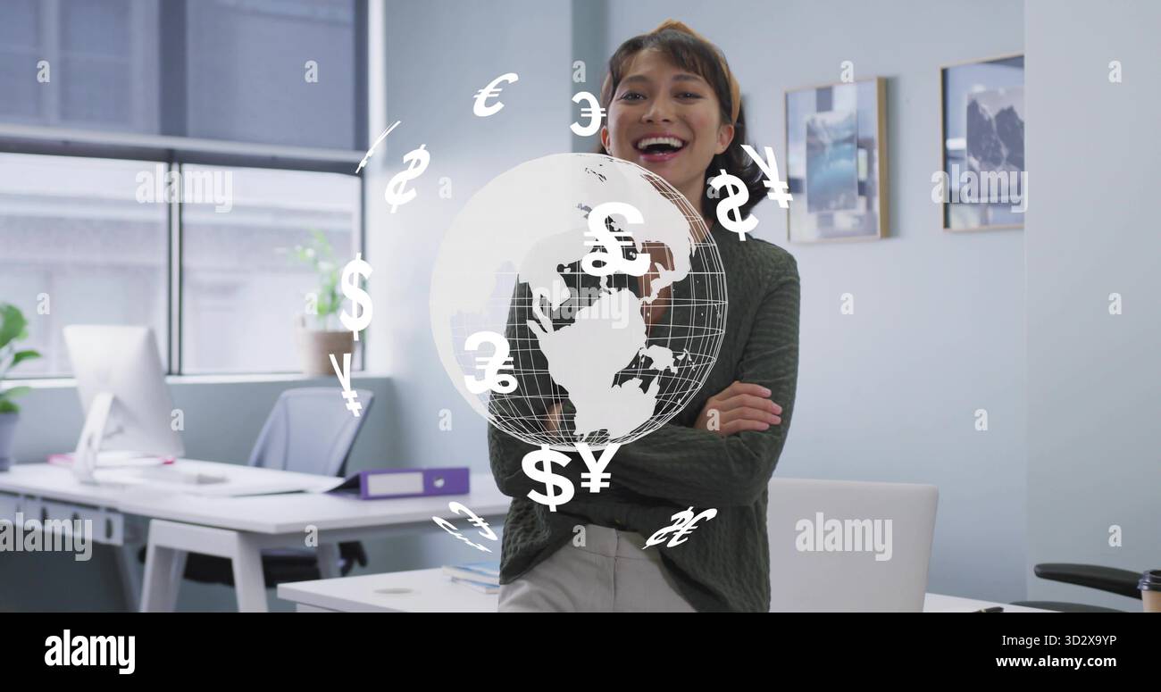 Donna d'affari asiatica sorridente appoggiata alla scrivania in ufficio, con globo olografico e simboli valutari Foto Stock