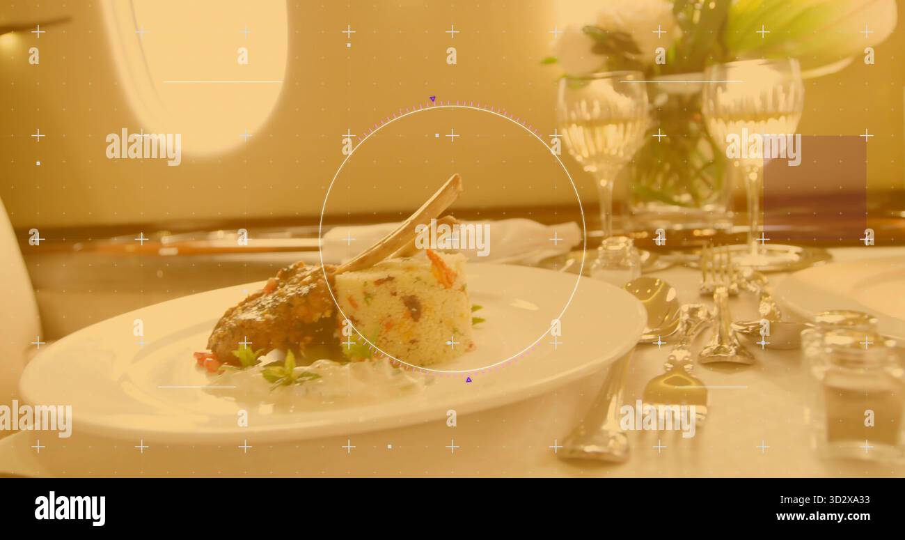 Costoletta di agnello alle erbe con couscous di verdure su piatto bianco in cabina di prima classe, con vaso di fiori Foto Stock