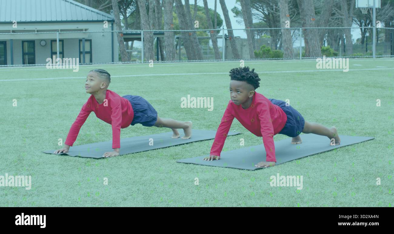 Due ragazzi che indossano magliette rosse e pantaloncini navy sul campo di erba, con tappetini Foto Stock