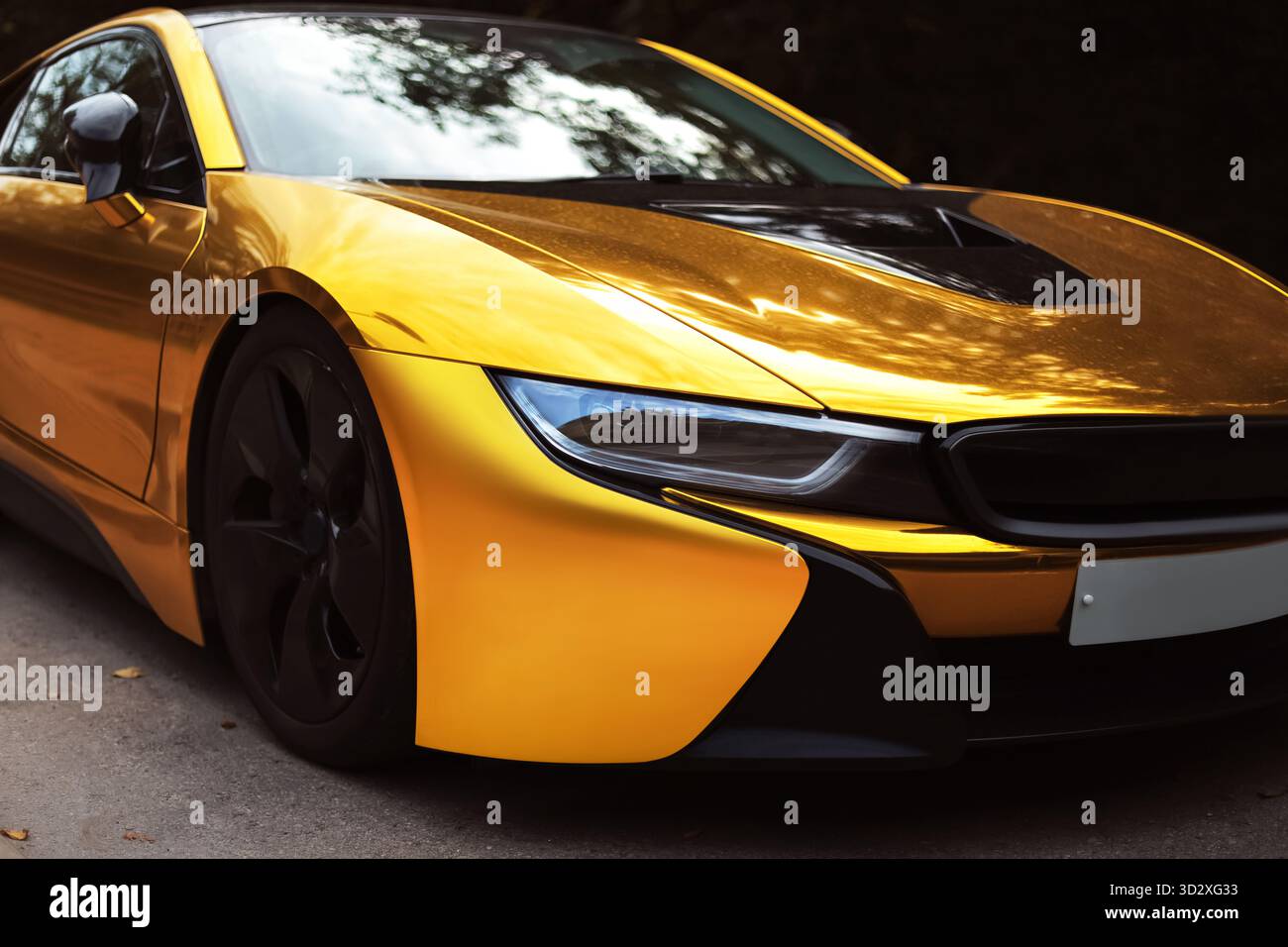 Un'elegante auto sportiva, coperta d'oro, è parcheggiata sulla strada. L'auto presenta un design moderno con dettagli neri e una finitura lucida. ph di alta qualità Foto Stock