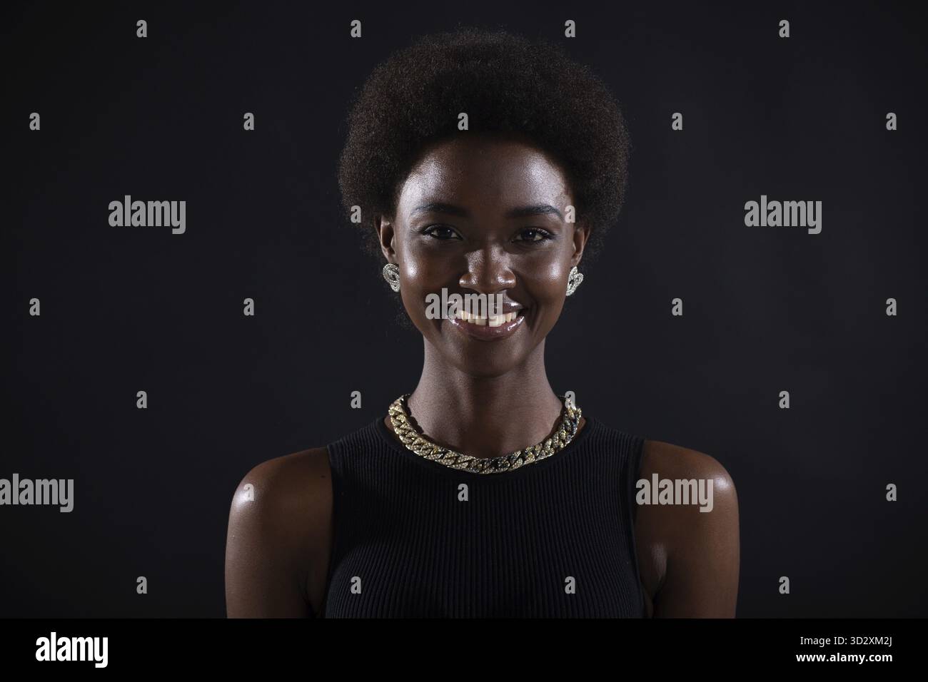 Primo piano di una donna afroamericana sorridente con acconciatura afro su sfondo nero Foto Stock