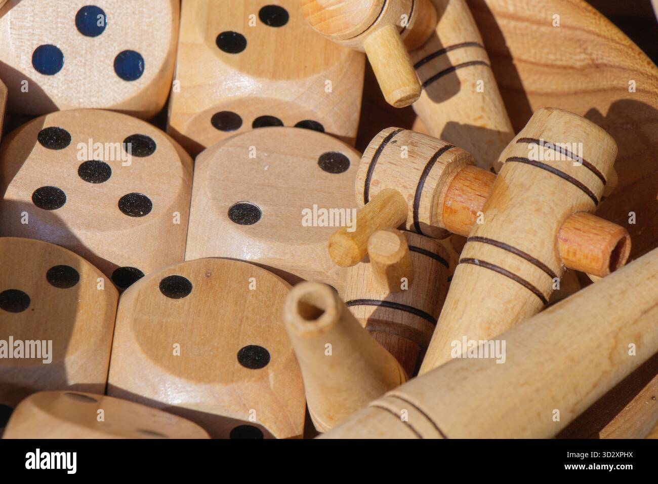 Una vista ravvicinata di dadi di legno artigianali e piccoli giocattoli in una ciotola presso un mercato artigianale locale. Le superfici lisce e lucide e le forme giocose si riflettono Foto Stock
