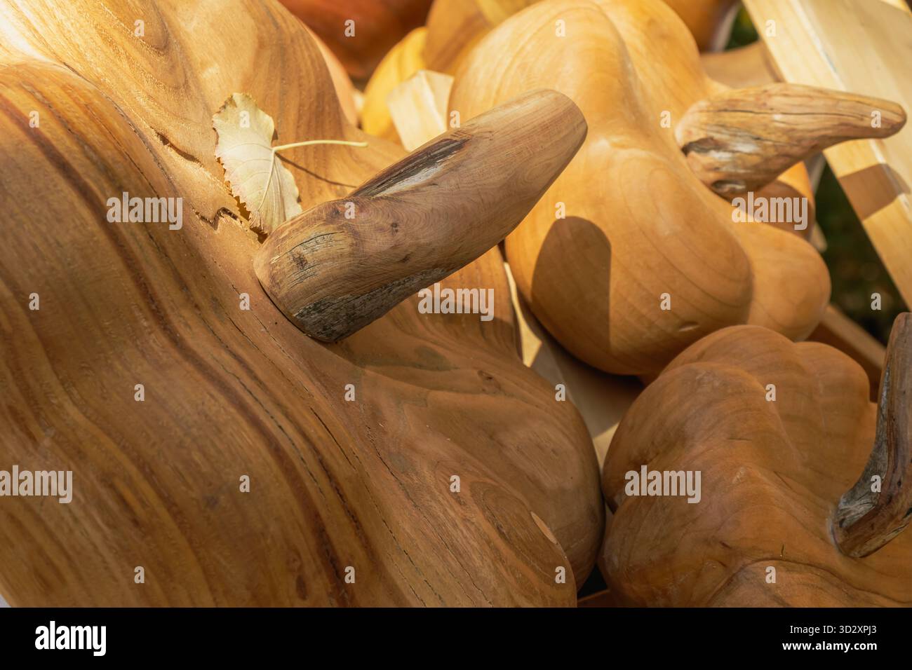 Vista ravvicinata di lisce sculture in legno artigianali esposte in un mercato artigianale. La calda luce del sole autunnale mette in risalto le texture naturali, organi Foto Stock