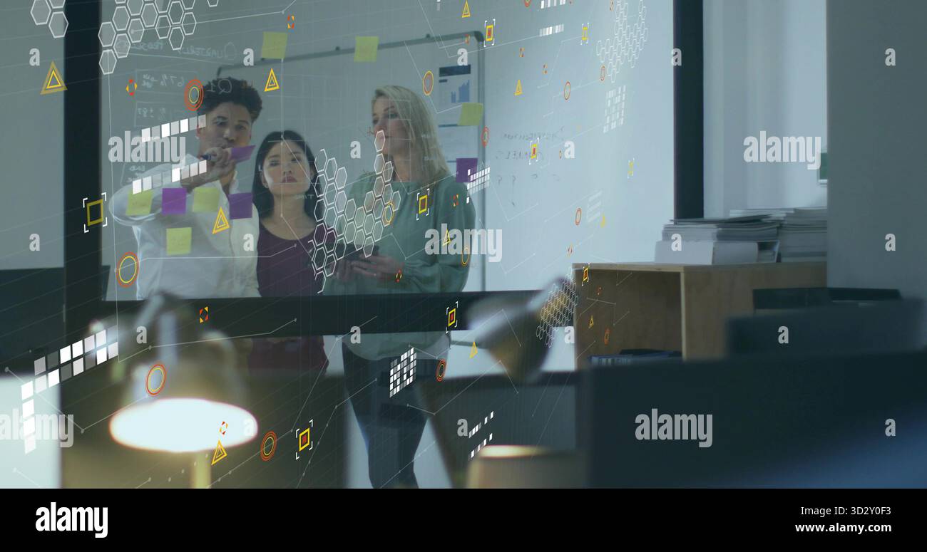 Tre professionisti che scrivono su una parete per la pianificazione del vetro in ufficio, con colleghi che esaminano gli appunti Foto Stock