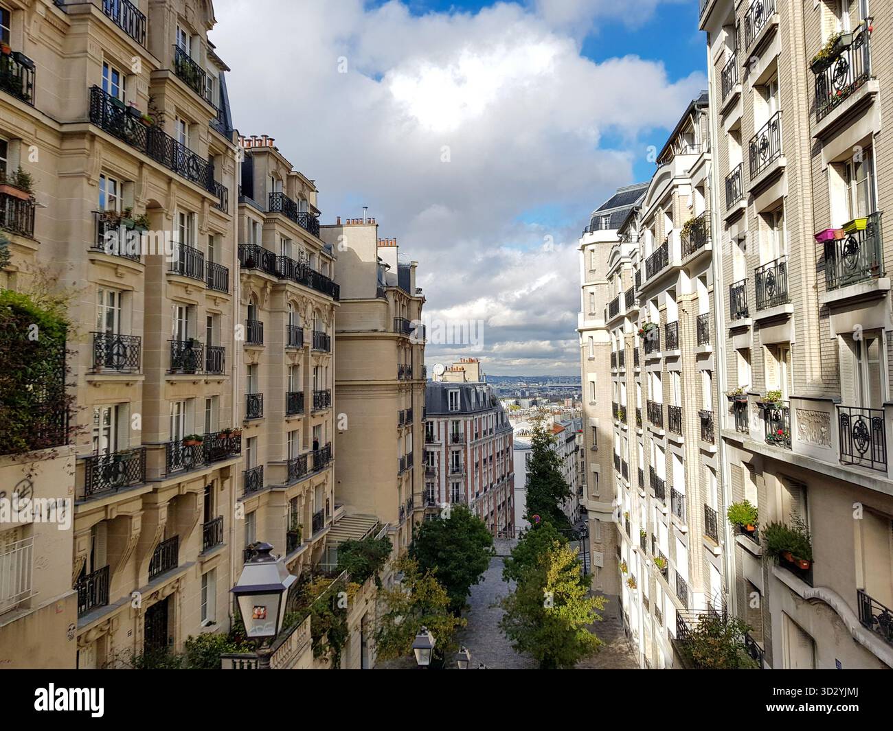 Edifici storici in stile Haussmann lungo una stretta strada acciottolata a Montmartre, Parigi, Francia, con balconi in ferro battuto Foto Stock