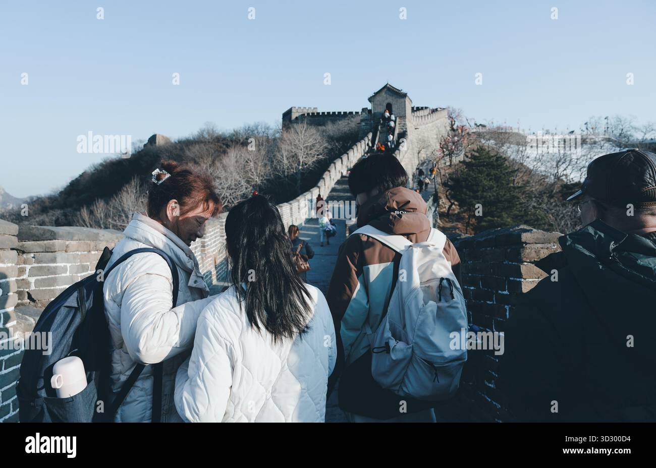Un gruppo di visitatori vestiti con giacche invernali e zaini si fermerà lungo la sezione Badaling della grande Muraglia Cinese Foto Stock