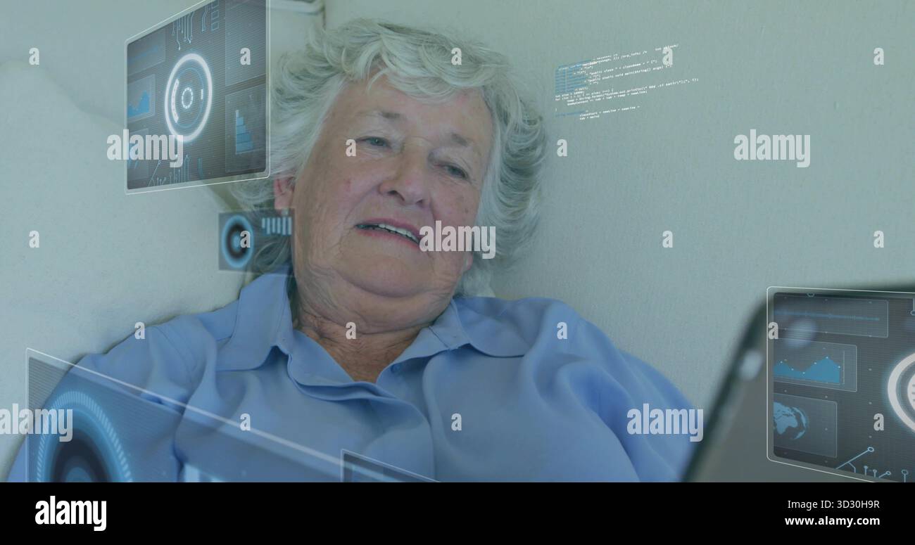 Donna anziana sdraiata che guarda il computer portatile in salotto, con pannelli di interfaccia digitali galleggianti Foto Stock