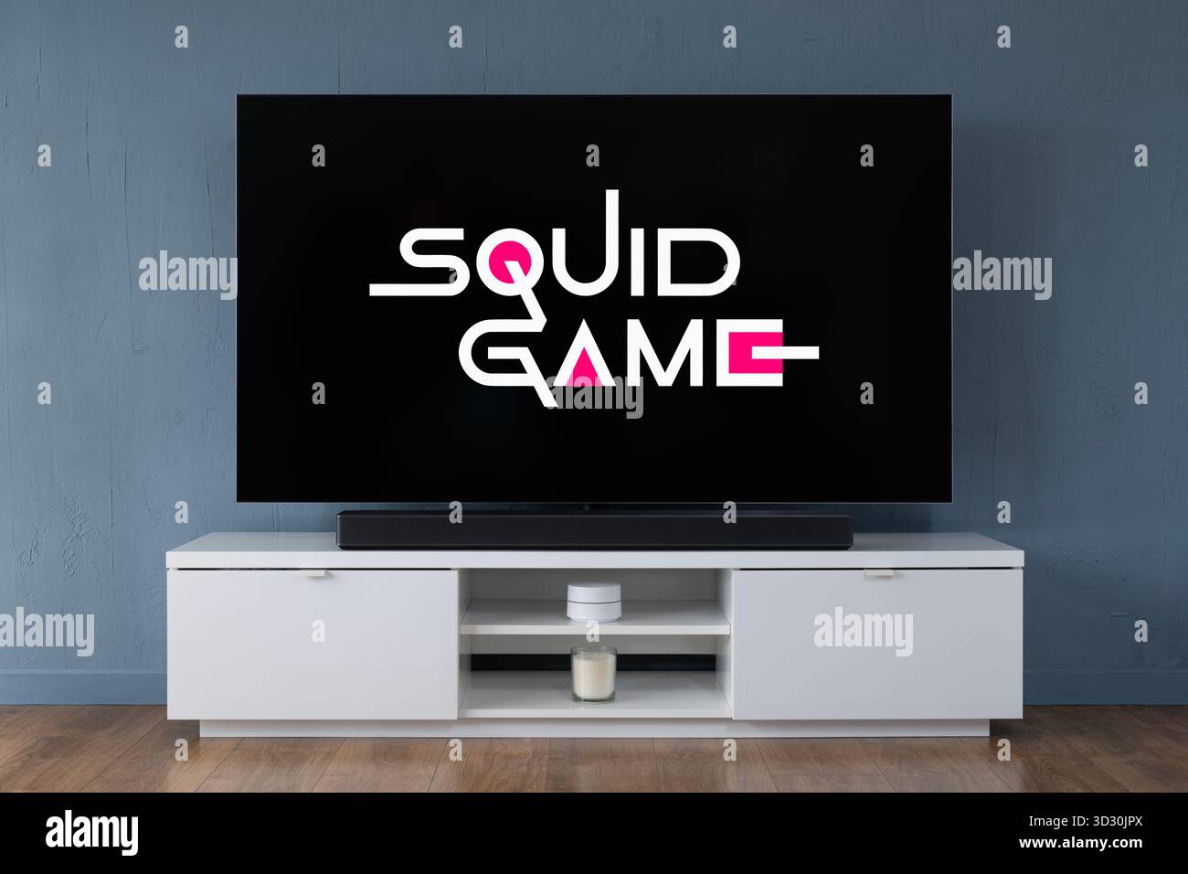 Un televisore OLED widescreen che mostra la scena introduttiva della serie TV Squid Game, visto in un salotto contemporaneo. Foto Stock