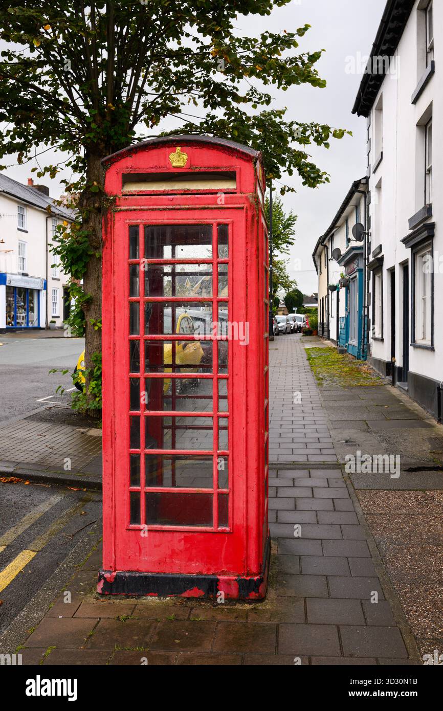 Llanidloes, Galles, Regno Unito - 1 settembre 2025; iconica cabina telefonica rossa britannica in condizioni meteorologiche su strada con corona Foto Stock