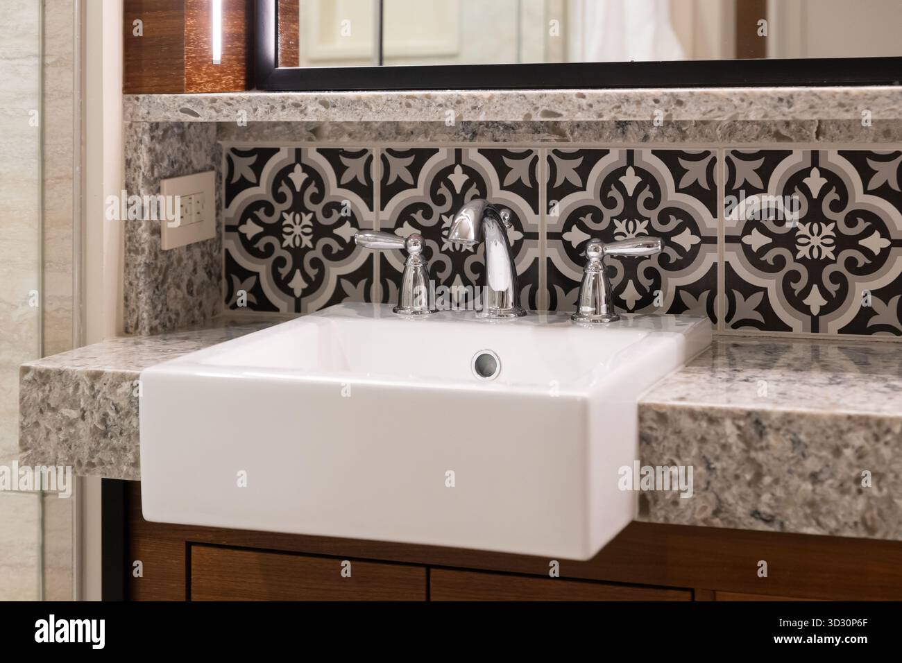 Un lavandino del bagno con un lavandino bianco della fattoria, un controsoffitto in pietra e una mensola circondata da armadietti in legno. Foto Stock