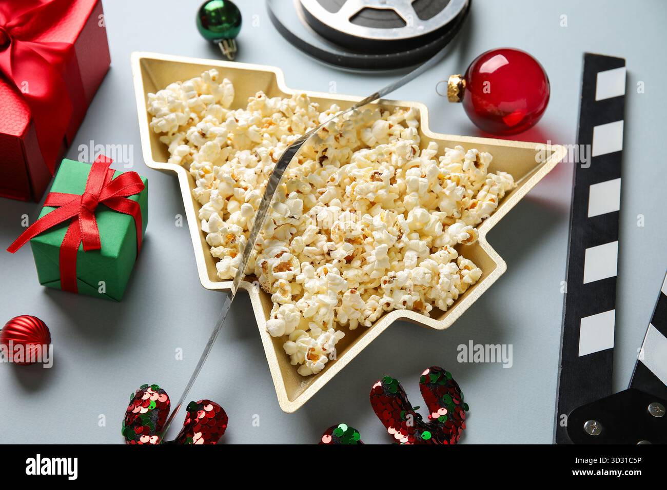 Piatto a forma di albero di Natale con popcorn, film, clapper, scatole regalo e decorazioni natalizie su sfondo bianco Foto Stock