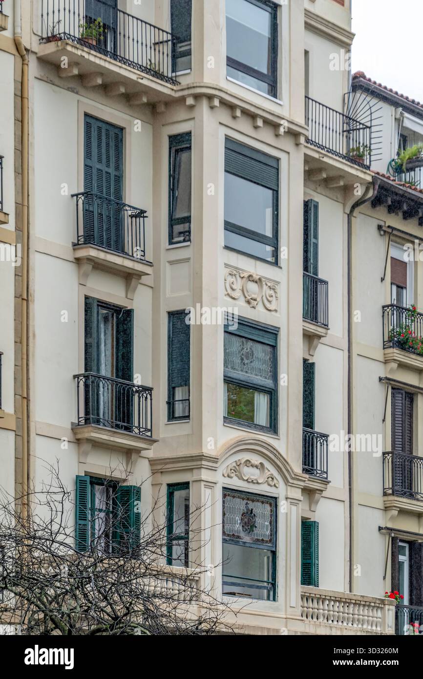 Facciata di un edificio residenziale tradizionale con balconi, dettagli ornati, tende verdi, architettura classica europea in un ambiente urbano spagnolo Foto Stock