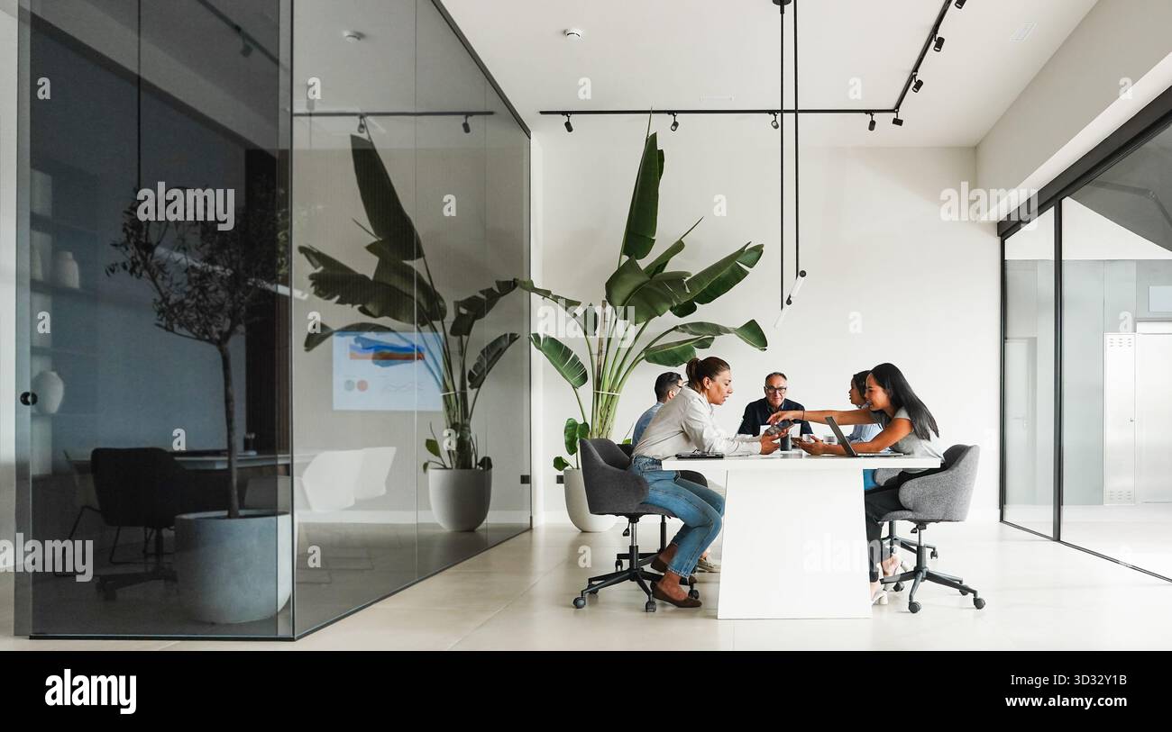 Uomini d'affari che condividono idee durante una riunione di lavoro di squadra all'interno di un ufficio minimale - colleghi multirazziali che discutono di un nuovo progetto finanziario - brainstorming e. Foto Stock