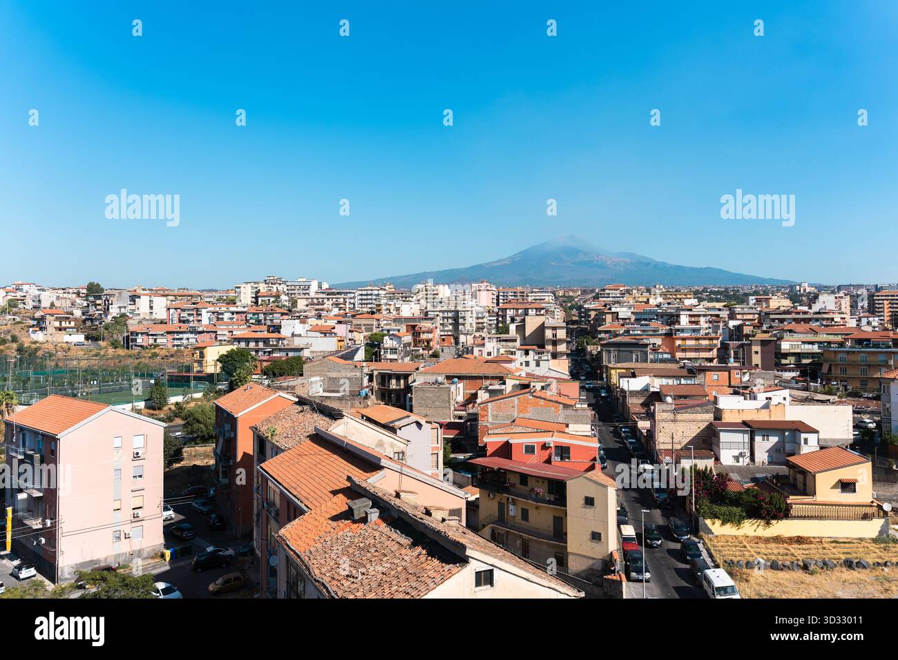 Una vista panoramica di Catania si estende sotto il limpido cielo siciliano, con l'Etna alto sullo sfondo. L'immagine cattura il warmt della città Foto Stock