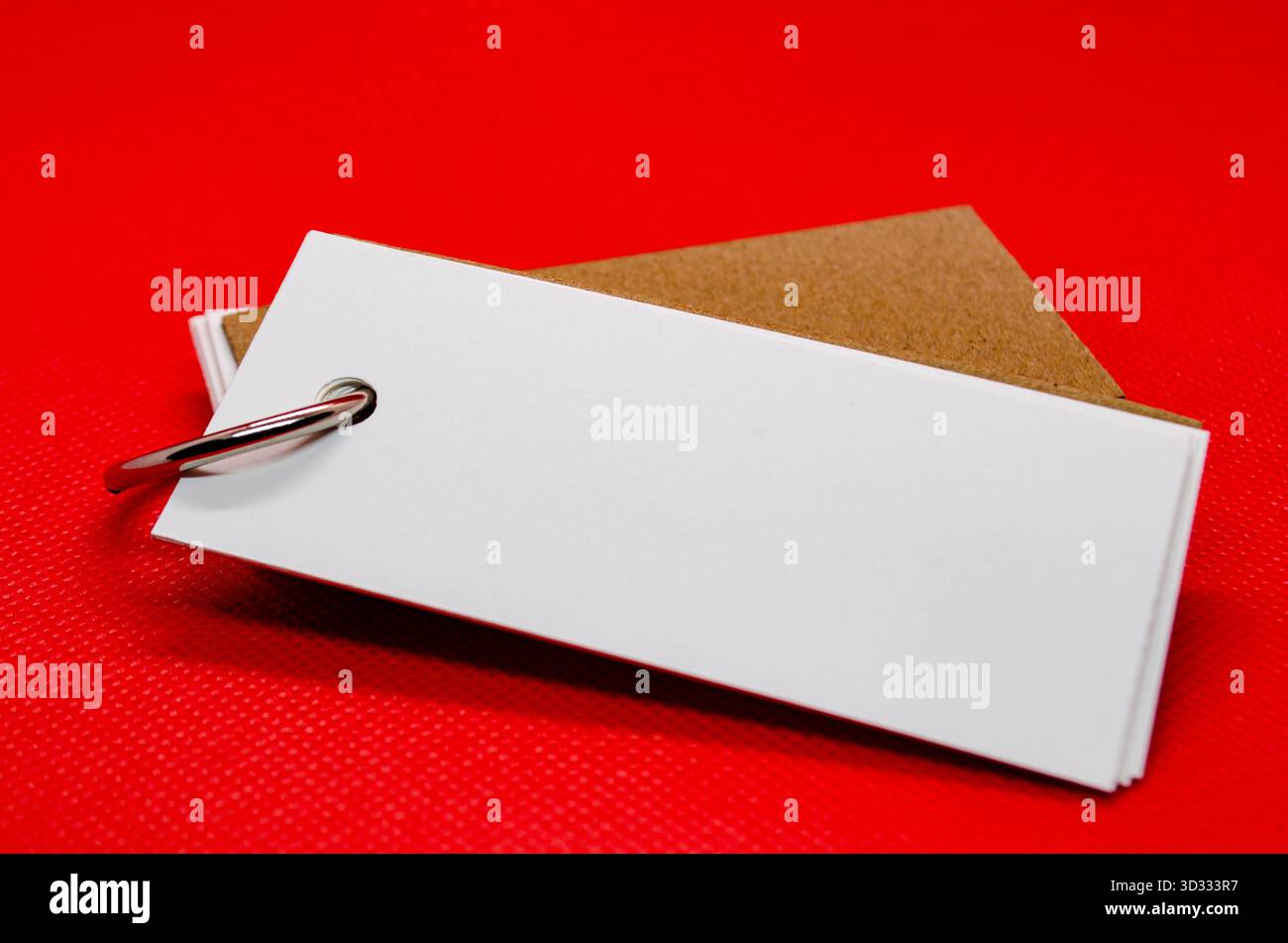 Primo piano del blocco note bianco a forma di banner con spazio personalizzabile per il testo sullo sfondo della copertina rossa. Concetto di spazio copiato Foto Stock