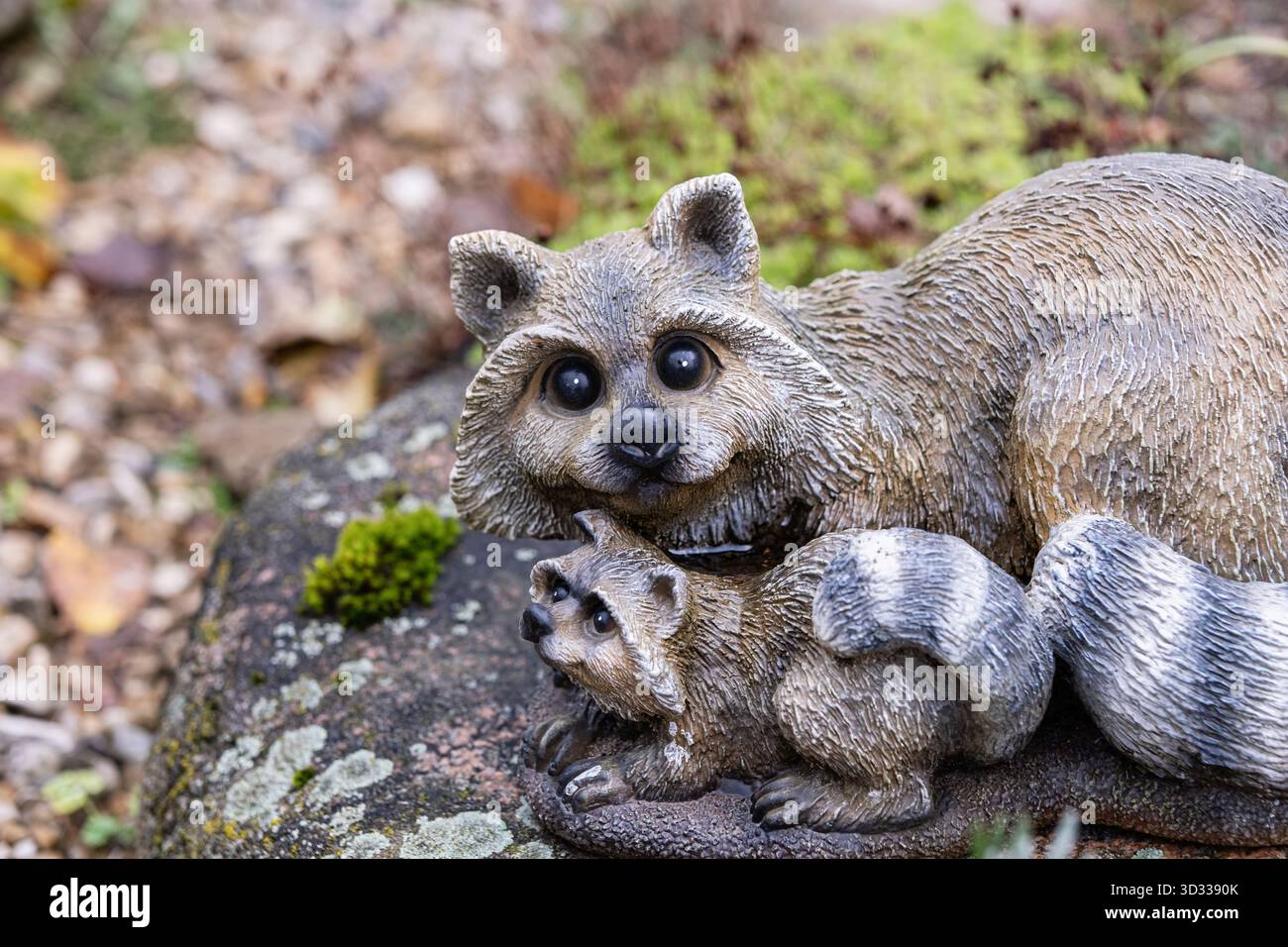 Statuetta di procione decorativa su una pietra in un ambiente da giardino. Perfetto per attività all'aperto, animali, natura e paesaggi. Ideale per decorazioni rustiche Foto Stock