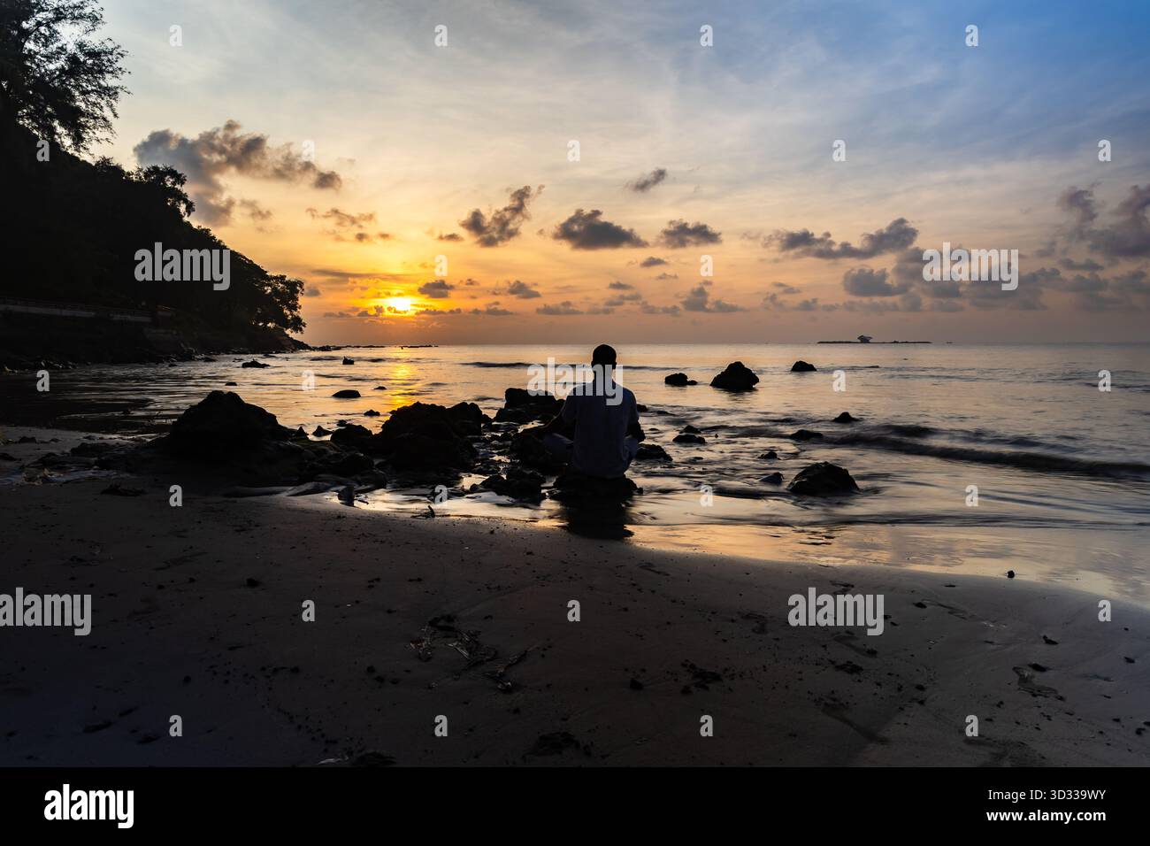 uomo che esegue benessere spirituale e meditazione su una spiaggia tropicale all'alba Foto Stock