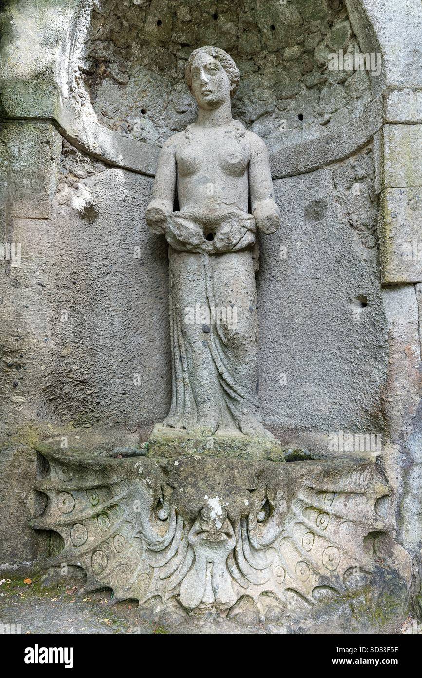Italia - Bomarzo - Sacro Bosco - Venere (Venere), dea in piedi in nicchia che regge un bacino di conchiglie sopra il font smerlato, figura rinascimentale nel Sacro Foto Stock