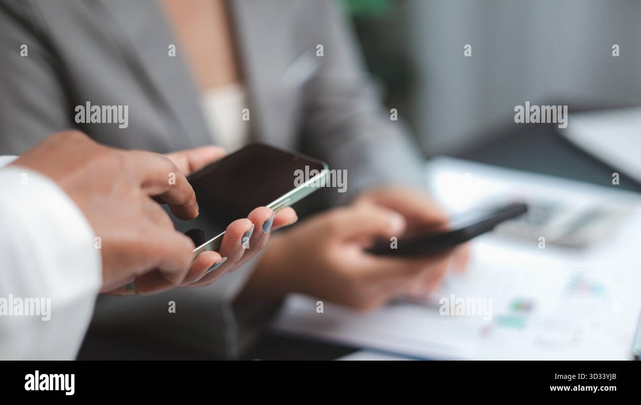 Team aziendale che utilizza lo smartphone per la comunicazione e la condivisione dei dati in ufficio. Concetto di lavoro di squadra, connessione digitale e tecnologia moderna in profess Foto Stock