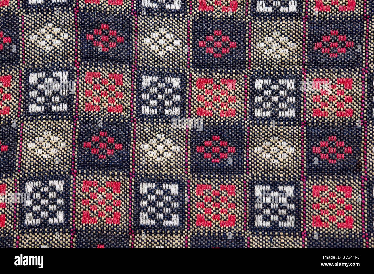 Primo piano di un tessuto vivace caratterizzato da un motivo geometrico intricato. Il design presenta quadrati ripetuti con motivi dettagliati Foto Stock