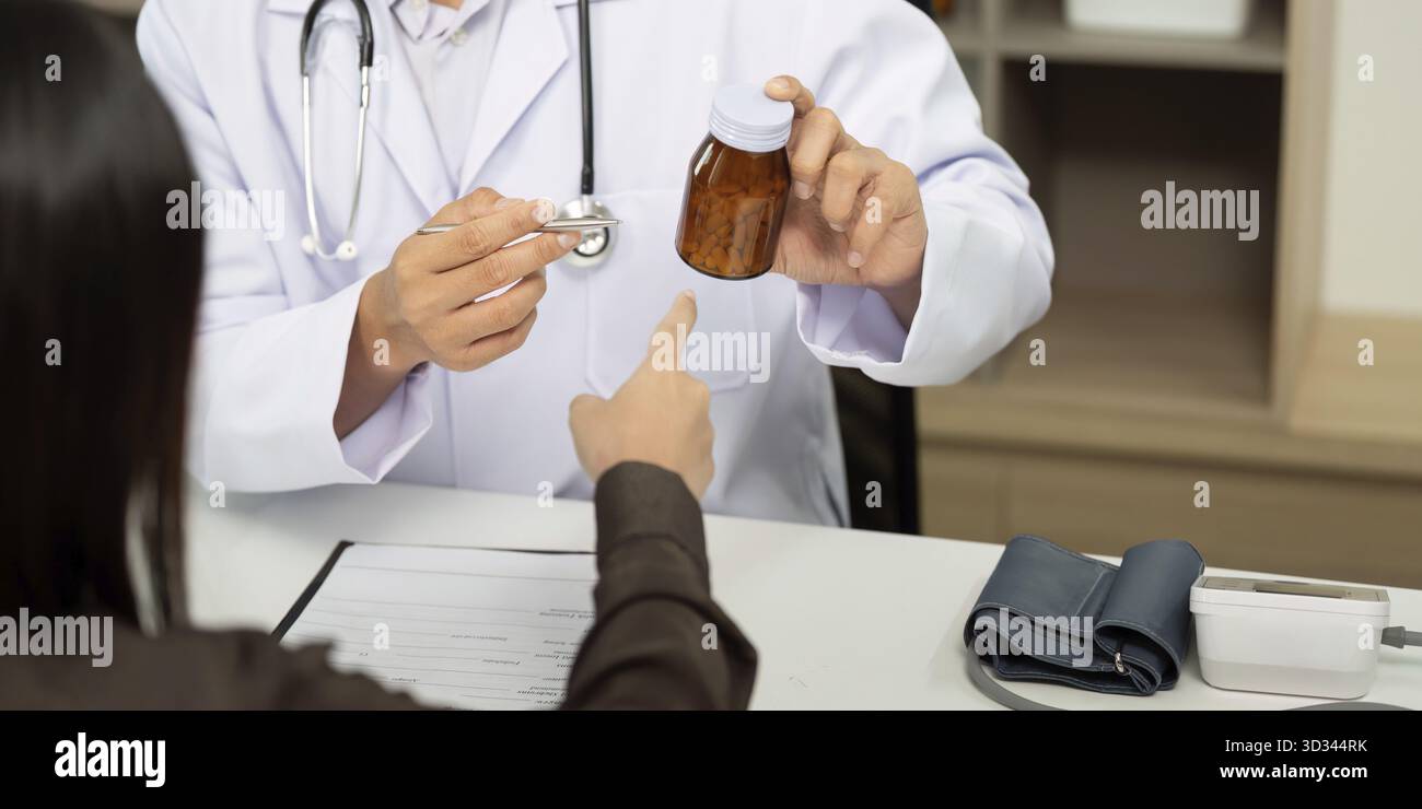 Un medico presenta un flacone di farmaco a un paziente, spiegandone l'uso e l'importanza nel piano di trattamento Foto Stock