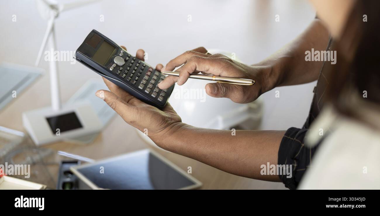 Un ingegnere che calcola i dati per progetti di ingegneria sostenibile, sottolineando precisione e responsabilità in un ambiente di lavoro moderno Foto Stock