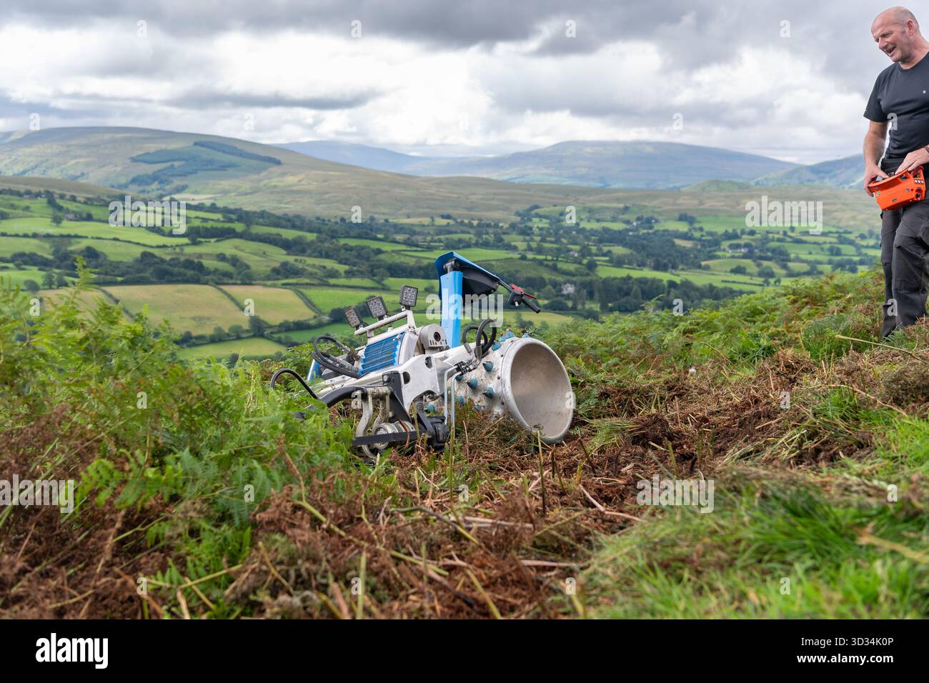 Agricoltore che utilizza un rasaerba telecomandato per tagliare Bracken su un pendio ripido, per controllare la diffusione dell'impianto invasivo. Howgill Fells in t Foto Stock