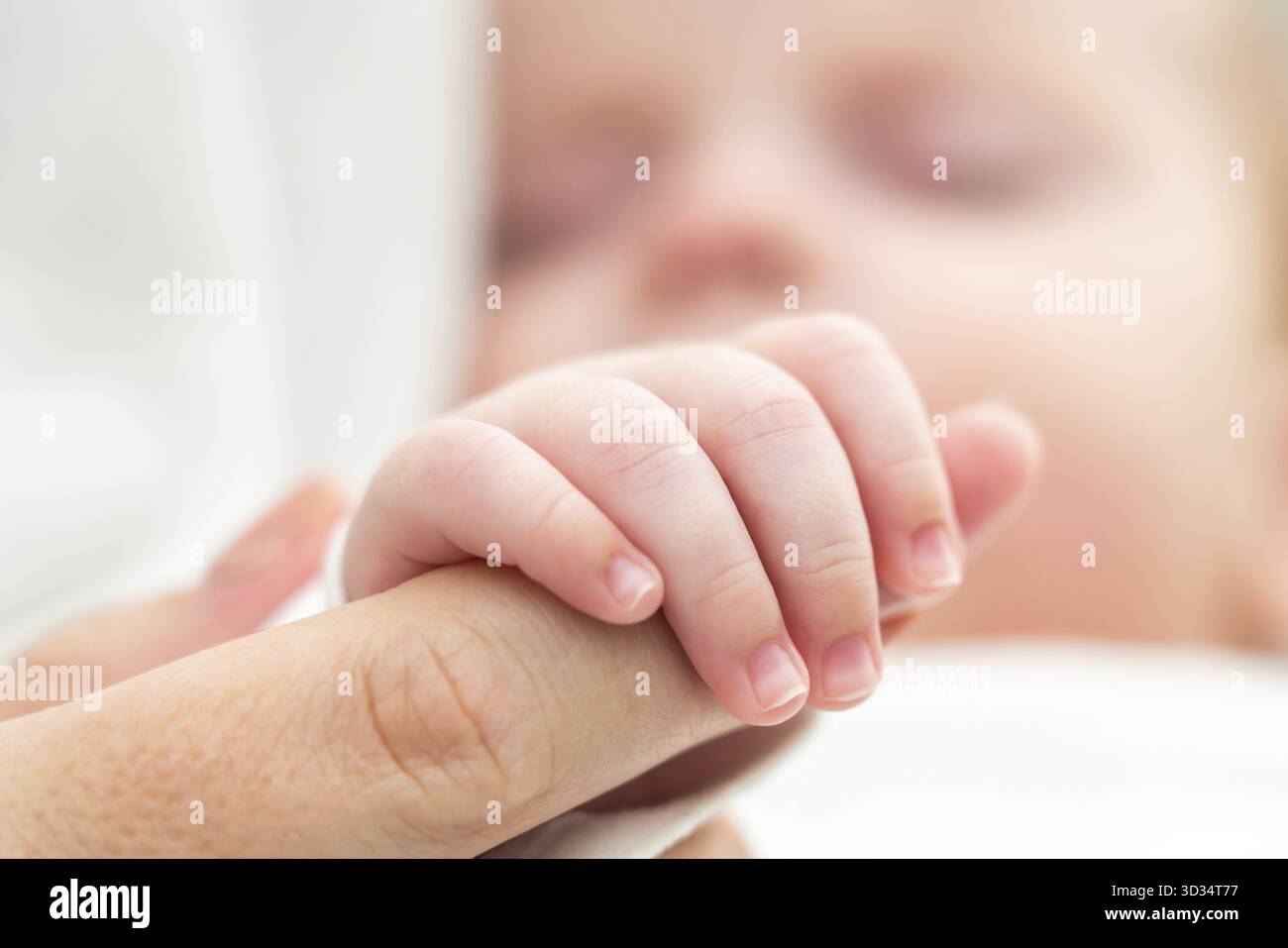 Il tocco tenero di un neonato addormentato, tenendo stretto il dito della madre, incarna amore e sicurezza Foto Stock